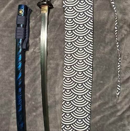Katana à côté de son fourreau bleu et de sa housse
